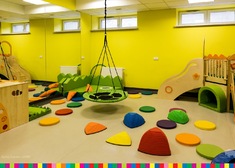 sala z kolorowymi przedmiotami do zabaw sensorycznych oraz wisząca huśtawka