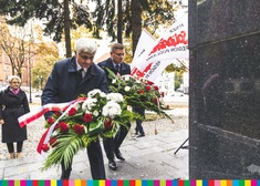 Dwaj mężczyźni skladają wieńce przed pomnikiem księdza Popiełuszki