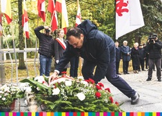 Mężczyzna składa kwiaty przed pomnikiem