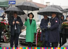 Wiesława Burnos, członek zarządu województwa stoi pod parasolem, po lewej mężczyzna w garniturze, po prawej stronie mężczyźni w mundurach, jeden z nich trzyma lampion