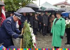 Wiesława Burnos, członek zarządu województwa oddaje hołd pod pomnikiem, na przeciwko niej wiązanka kwiatów  