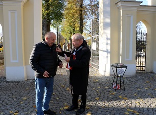 Marek Olbryś przed cmentarzem nakleja nalepki pomagającym