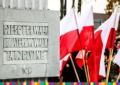Zdjęcie pomnika, obok flagi