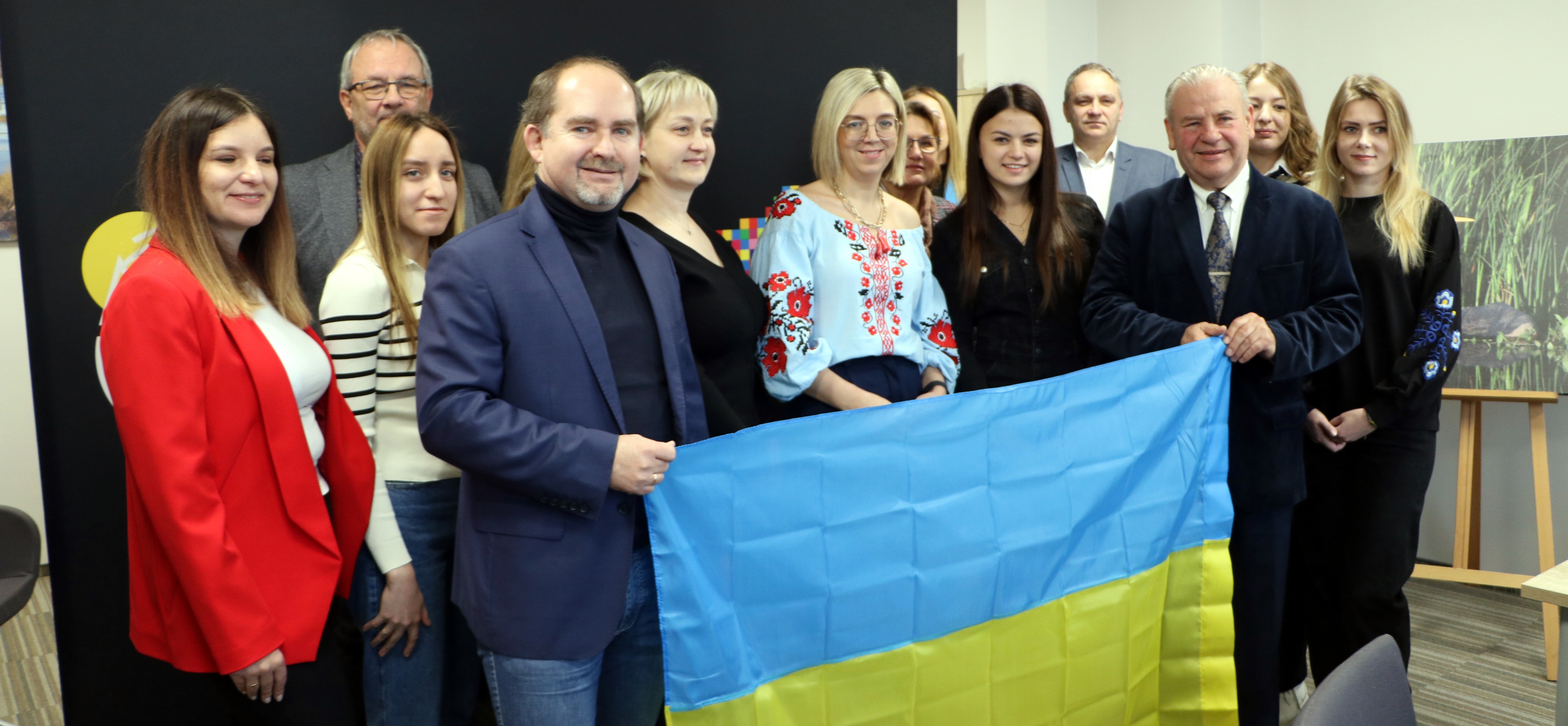 Osoby trzymające ukraińską flagę, pozując do wspólnego zdjęcia