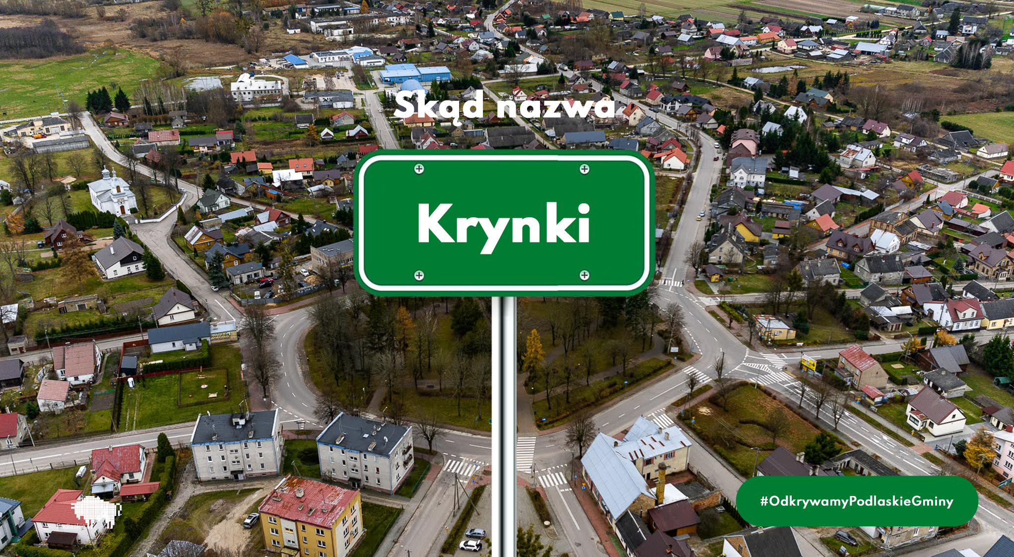 Tablica z napisem Krynki w tle widok z drona na tę miejscowość