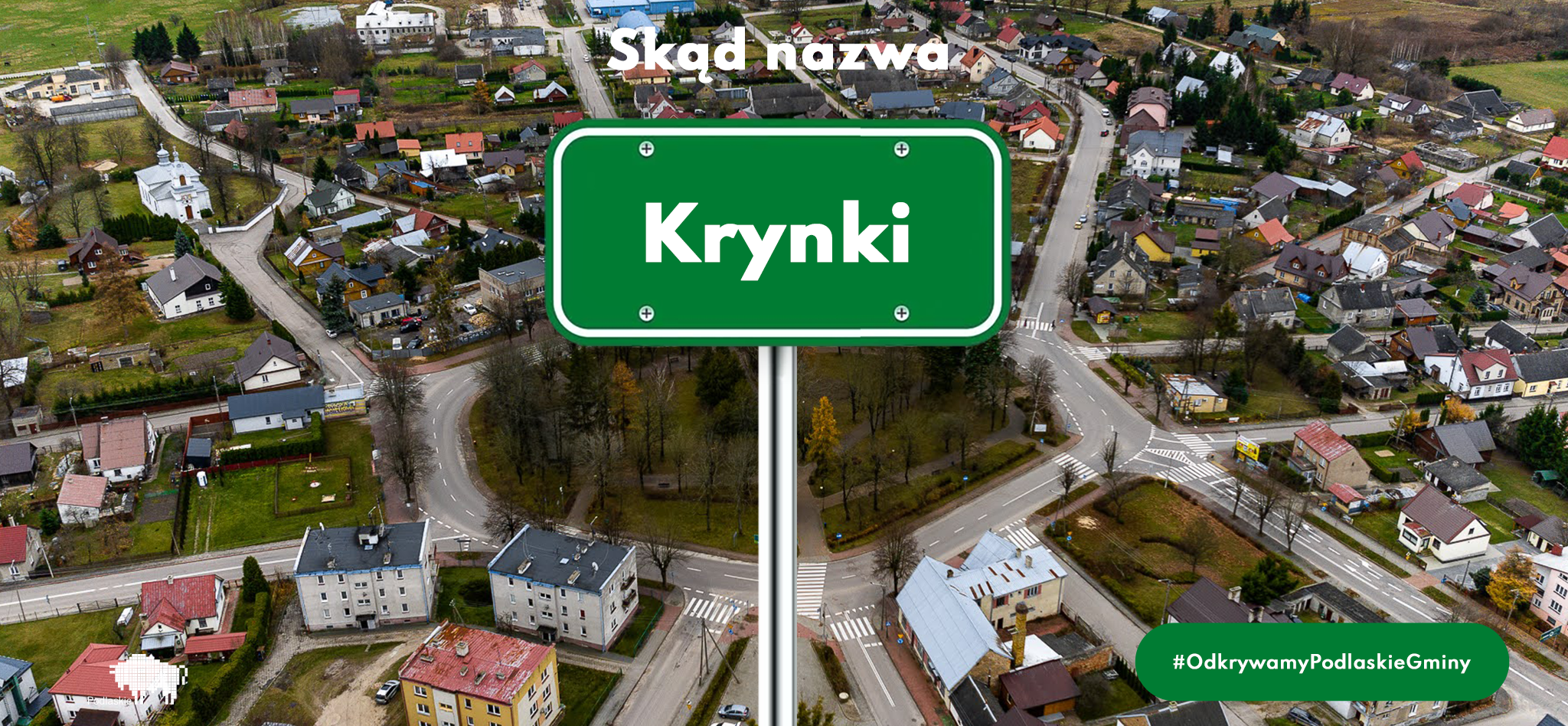 Tablica z napisem Krynki w tle widok z drona na tę miejscowość