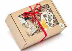 pudełko prezentowe owinięte czerwoną wstążką, w którym znajduje się świeca o zapachu grzanego wina oraz zawieszka z wosku sojowego 