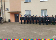 strażacy stojący w rzędzie przed budynkiem OSP 