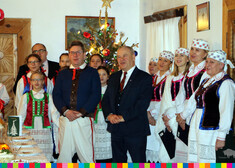 Wicemarszałek Marek Olbryś oraz kobiety, dzieci i mężczyzna w strojach ludowych, za nimi choinka, po lewej stronie mężczyzna w garniturze   
