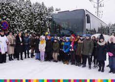 Zgromadzone dzieci, oficjele i duchowny na tle nowego autobusu
