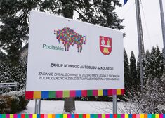 Tablica z napisem Zakup nowego autokaru, znajduje się na niej również logo województwa podlaskiego oraz gminy Nowinka