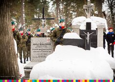 Zaśnieżony grób oraz stojący obok żołnierz