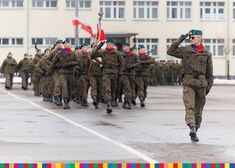 Maszerujący żołnierze w szyku z flagą Polski oraz sztandarem