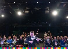 Grający skrzypek na tle publiczności  