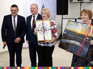 Członek zarządu Marek Olbryś, oficjel i dwie kobiety trzymające obrazy