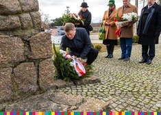 Marek Malinowski składa kwiaty pod pomnikiem.