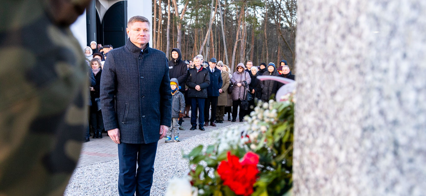 Marek Malinowski stoi przed pomnikiem żołnierza wyklętego.