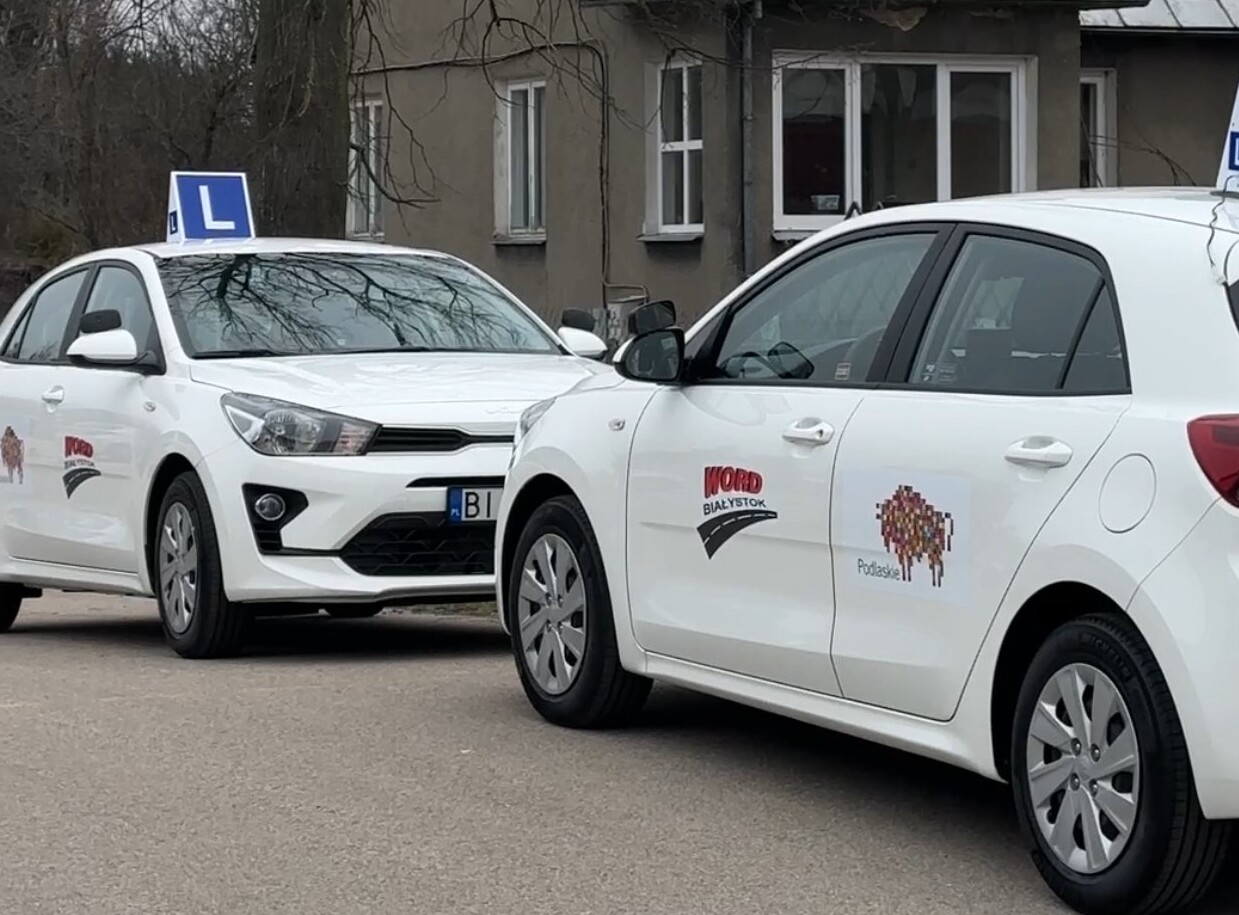Dwa białe auta z logotypem województwa podlaskiego i WORDu