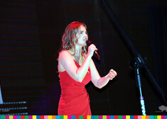 Kobieta w czerwonej sukience śpiewa przez mikrofon