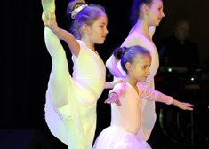 Trzy dziewczyny w białych strojach tańczą