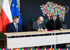 Marszałek Kosicki podpisuje dokument, obok siedzą członek zarządu Malinowski i ksiądz Dobroński