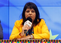 Kobieta w żółtym żakiecie przemawia przez mikrofon