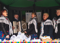 Grający na akordeonie mężczyzna i śpiewające kobiety w strojach ludowych