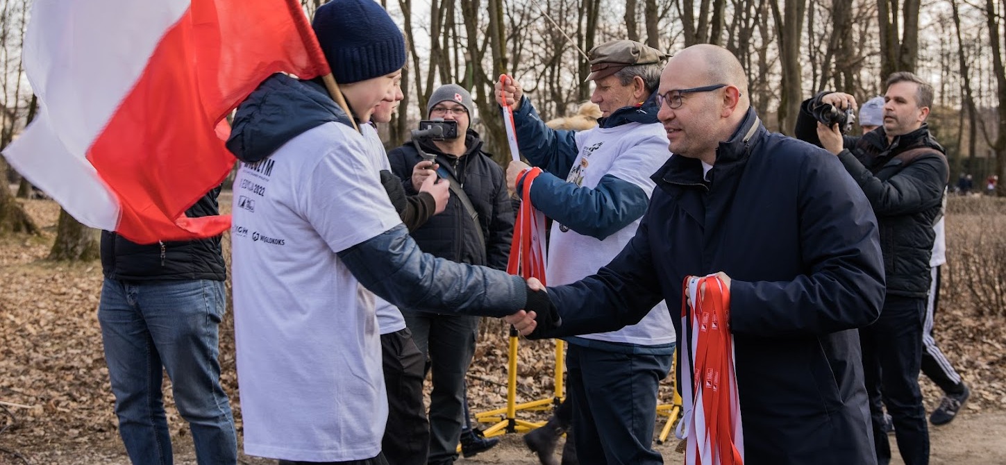 Marszałek Artur Kosicki wręcza medal uczestnikowi biegu