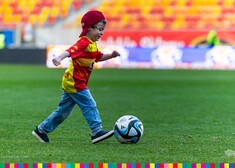 Mały chłopiec kopie piłkę na stadionie