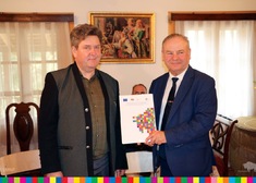 Marszałek Olbryś oraz dyrektor Jakimowicz trzymają dokument z logotypem województwa podlaskiego