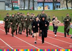 Dzieci, mundurowi biegnący po bieżni lekkoatletycznej