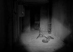 Czarno biała fotografia z leżącym rowerem na posadce w piwnicy