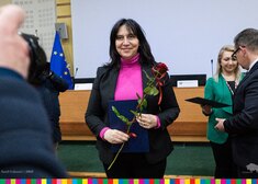 Radna pozuje do zdjęcia trzymając kwiaty.