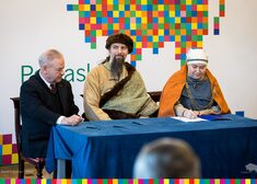 Marek Olbryś i dwie osoby w strojach ludowych podpisują umowy.