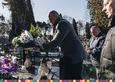 Krzysztof Szeweluk składa kwiaty na grobie w asyście dwóch osób
