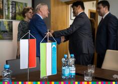 Flagi Polski i Uzbekistanu stojące w pierwszym planie.