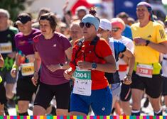 Kobieta biegnie wśród tłumu sportowców.