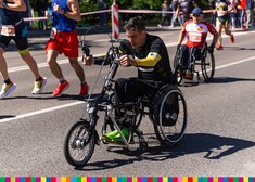 Niepełnosprawny zawodnik uczestniczy w biegu jadąc wózkiem.