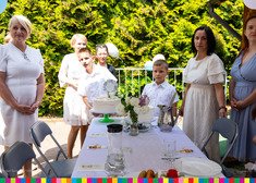 Uczestnicy komunii stoją przed stołem z tortami.