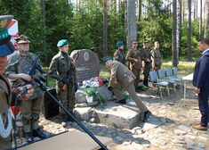 Żołnierz składa kwiaty pod pomnikiem.