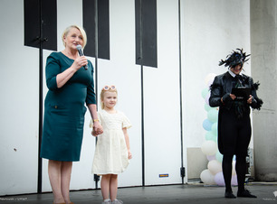 Wiesława Burnos stoi obok dziewczynki i przemawia do mikrofonu.
