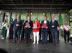 Laureaci odznak honorowych województwa na scenie z przedstawicielami samorządu.