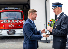 Marek Malinowski przekazuje podarunek strażakowi.