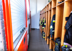 Wyposażenie strażackie w szafach obok wozu strażackiego.