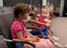 Dzieci siedzą na krzesłach w sali konferencyjnej