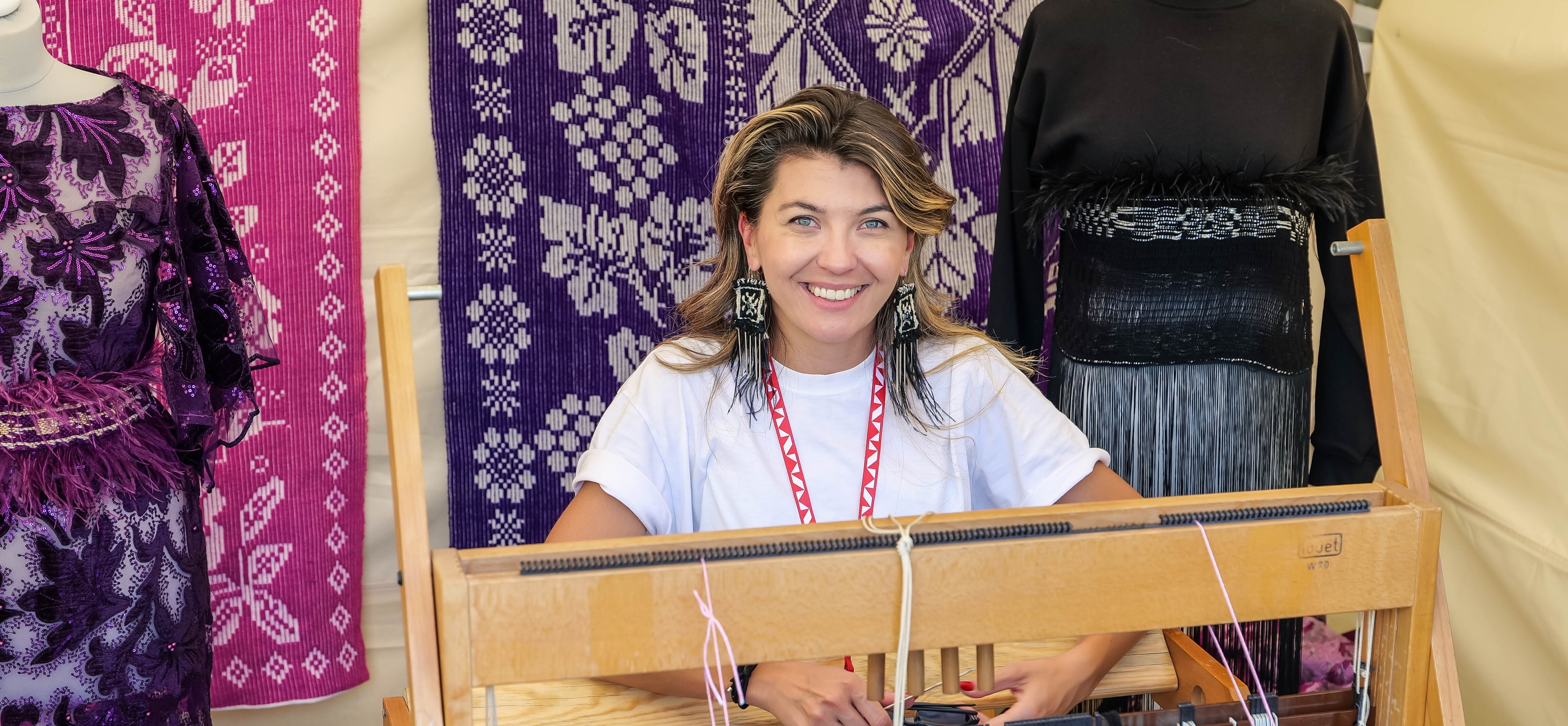 Uśmiechnięta kobieta siedzi za maszyną tkacką