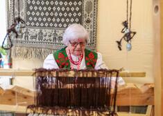 Starsza kobieta siedzi za maszyną do tkania