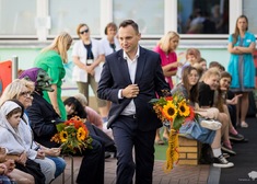 Dyrektor Gabinetu Marszałka idzie z wiązanką kwiatów wśród tłumu