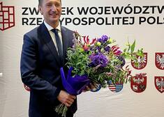 Marszałek Olgierd Geblewicz stoi z kwiatami