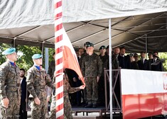 Żołnierze wciągają flagę na maszt. Oficjele patrzą
